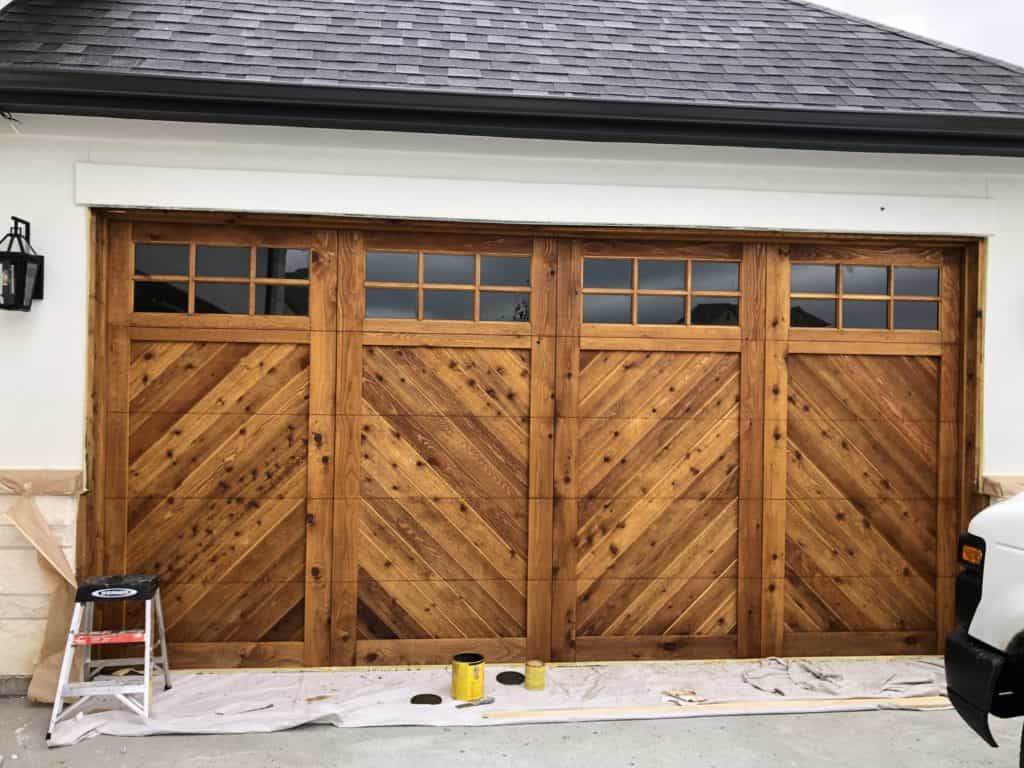 Rich stained wooden garage door in Edmond Oklahoma with glass windows, showcasing custom grage door staining and sealing services at Patriot Stain and Seal.